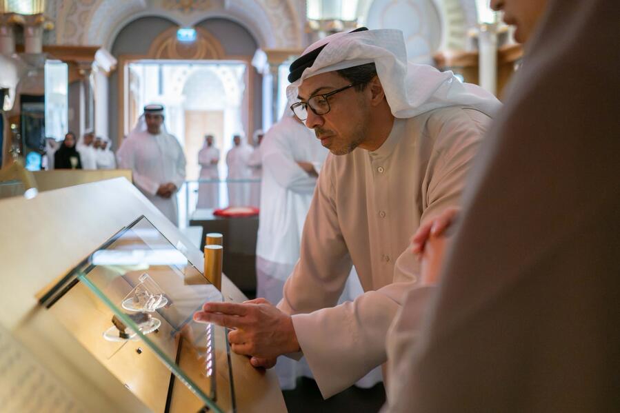 Visitor taking a closer look at objects inside an illuminated inclined display case at Qasr Al Watan.